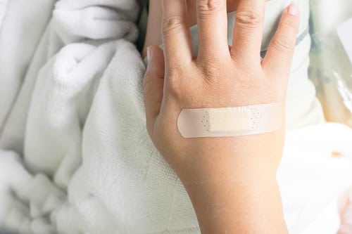 a plaster close wound on back hand on the bed in hospital