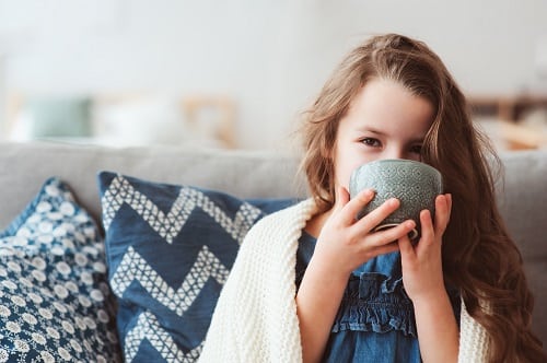 child girl drinking hot tea to recover from flu. Healing kids and protect immunity from seasonal virus, health concept